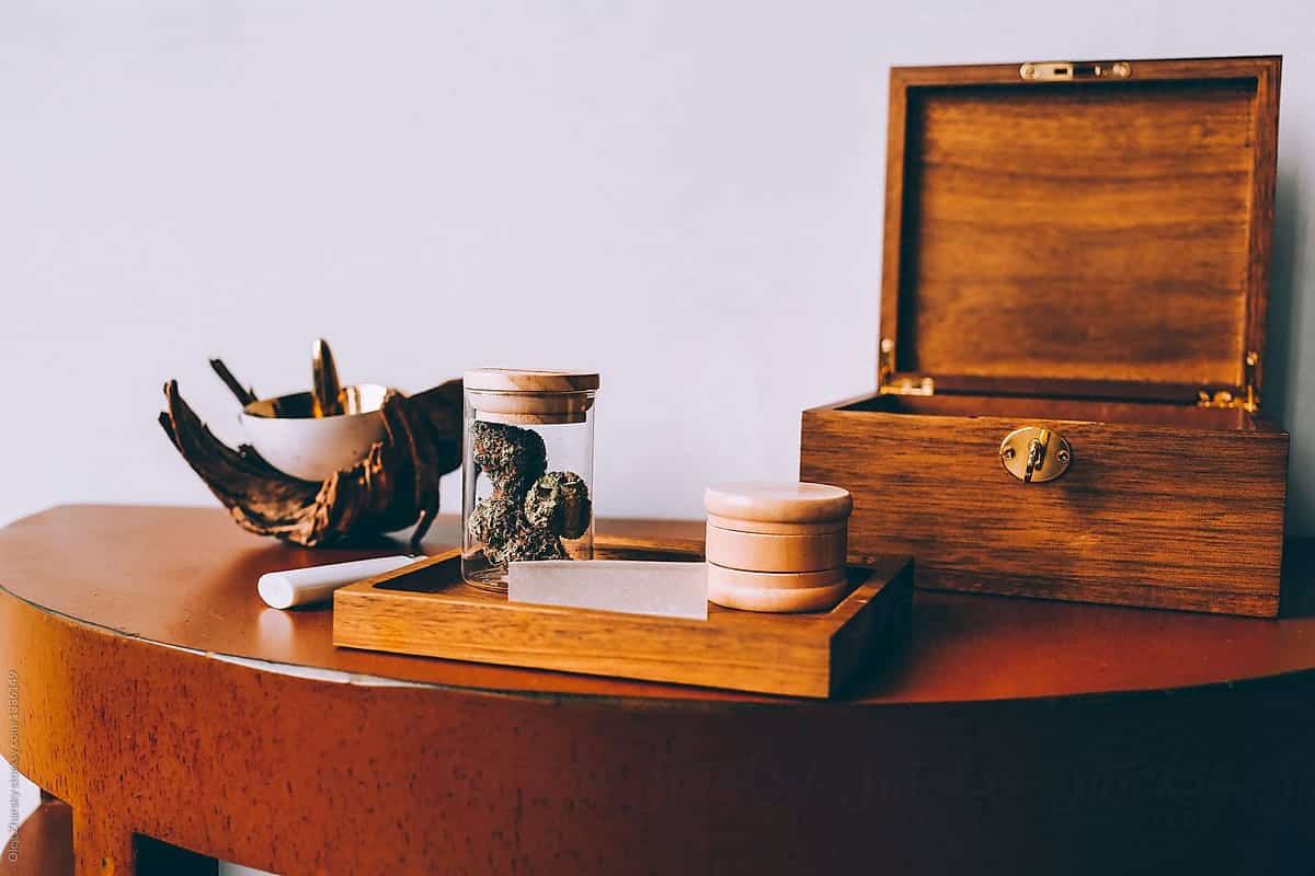 Wooden Stash box on a wood table alongside a glass jar of cannabis