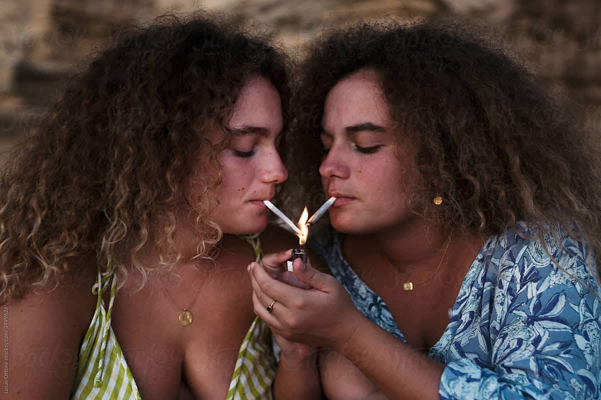 Two curly haired women smoking cannabis together but can experience a different experience