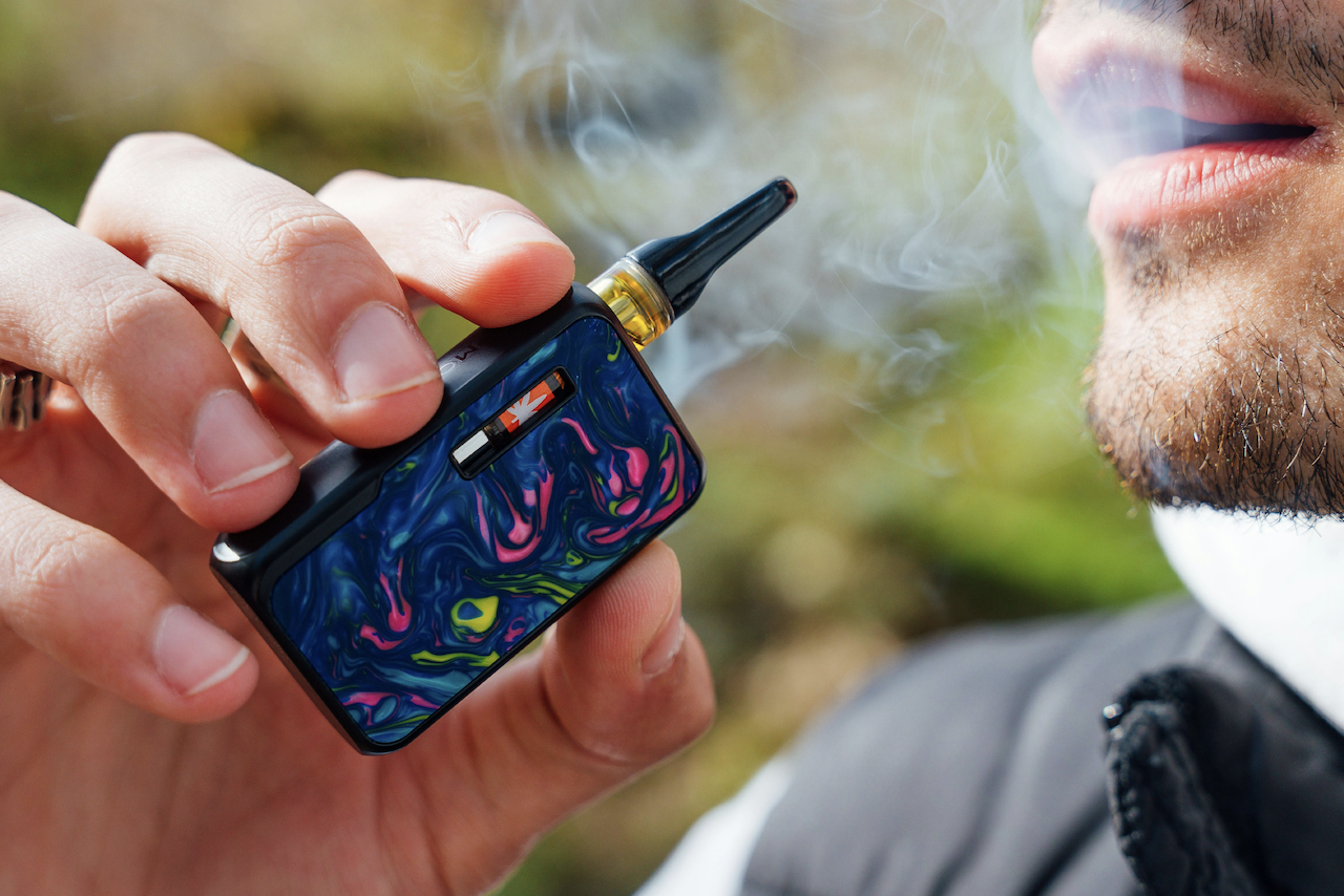 Close up of a man smoking a retro cannabis vape.