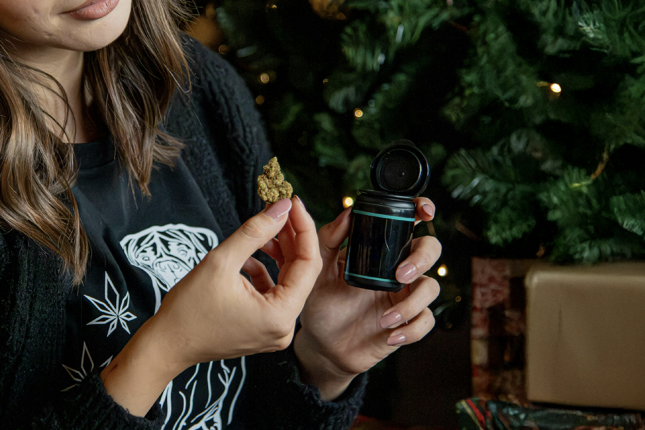 Woman holding jar of weed need a Christmas tree.