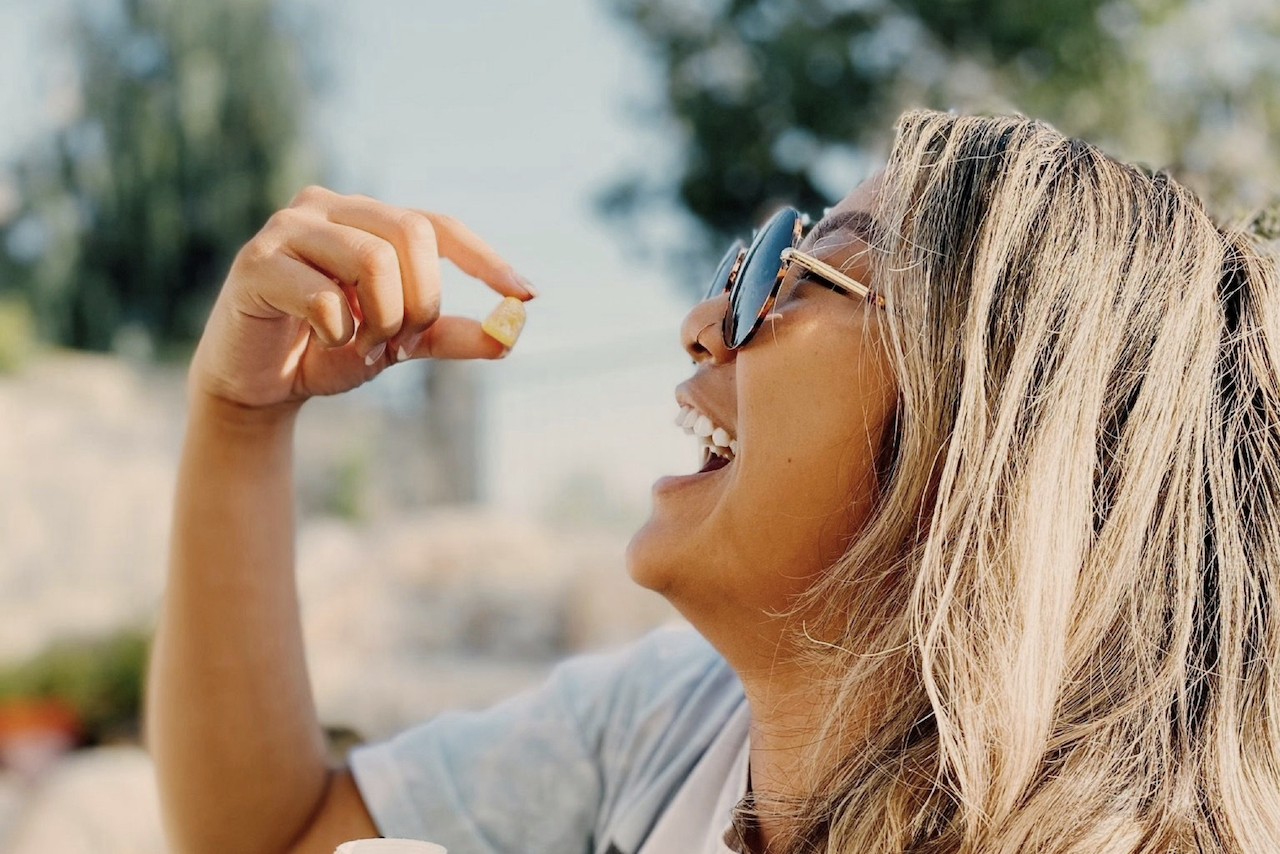 Happy woman eating a yellow THC lozenge.