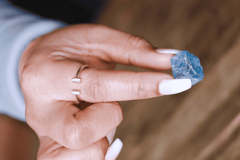 Woman hand holding a blue, sugar coated RSO gummy.