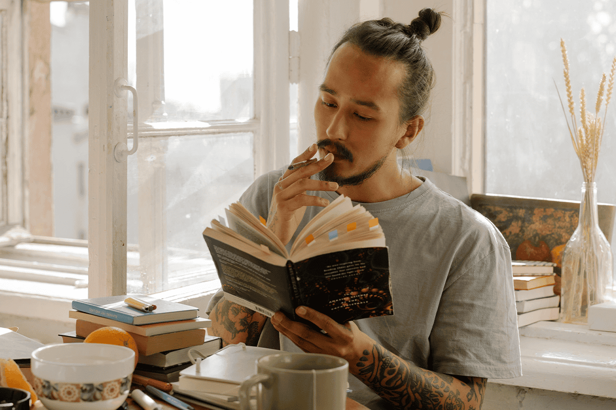 Man smoking a joint while reading a book.